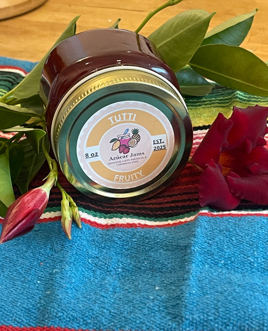 A jar of Tuitii Arizcar Jam with a 'Fruity' label, styled on a colorful Mexican serape blanket with green leaves and red flowers.